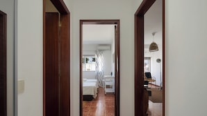 Un pasillo que conduce a un dormitorio con una cama, un escritorio y una silla.