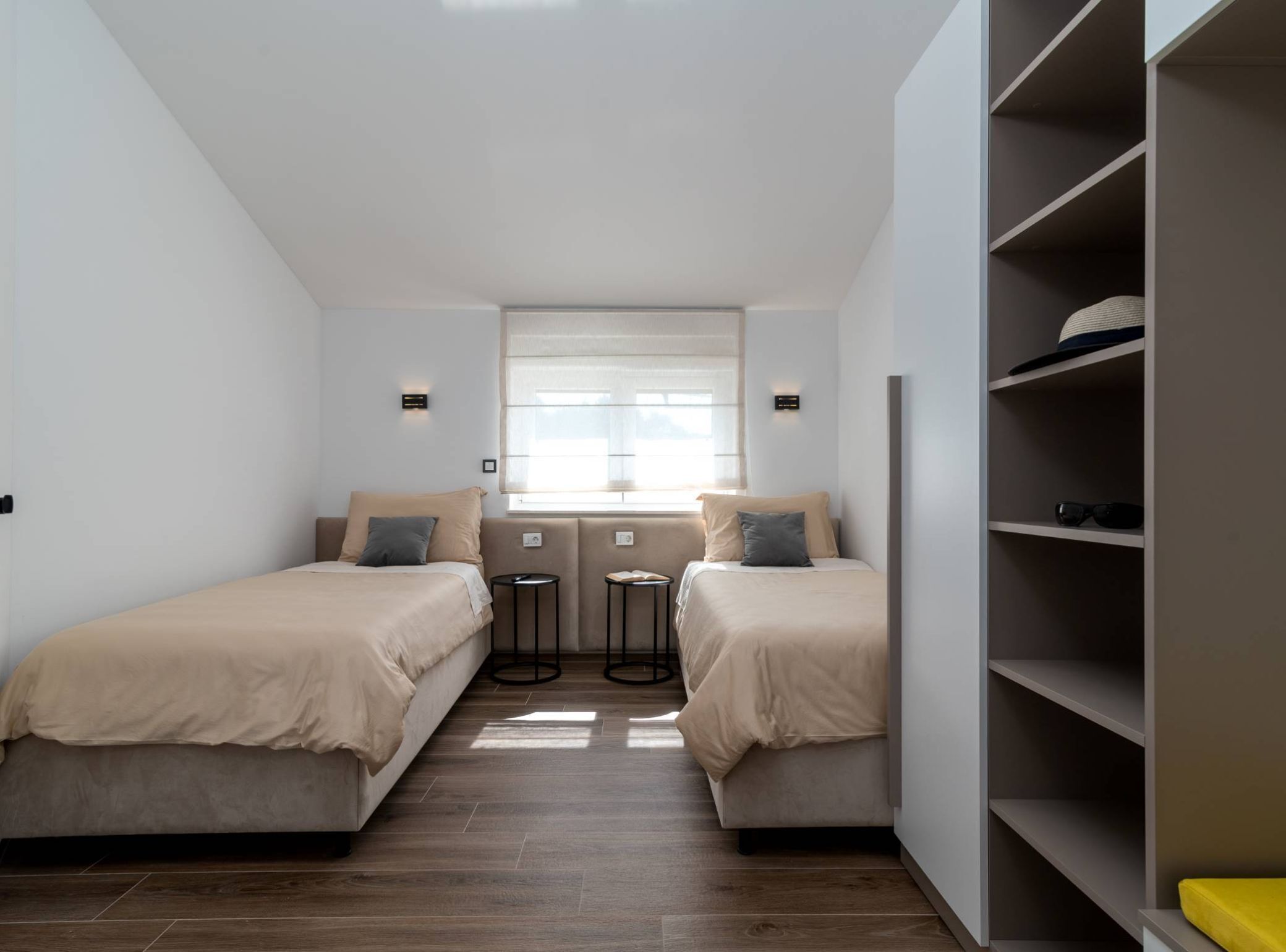 Ein Schlafzimmer mit zwei Betten, einem Fenster, einem Kleiderschrank und einem kleinen Tisch.