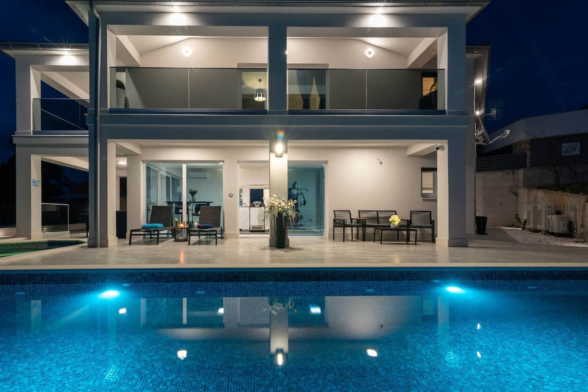 Ein modernes, zweistöckiges Haus mit Schwimmbecken im Vordergrund.
