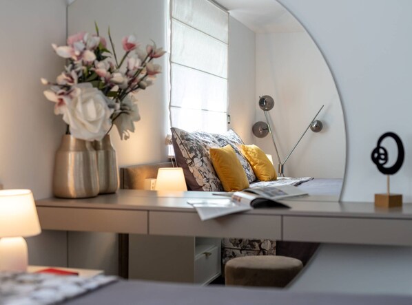 A bedroom with a bed, a bedside table with a lamp, a vase with flowers, and a wall-mounted clock. - Luminous Infinity Villa With Pool and Gym (Rogoznica)