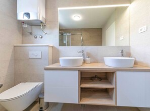 Un baño moderno con dos lavamanos, inodoro y ducha.