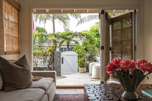A cozy living area with a sofa, a coffee table, and a vase of flowers. - Nantucket-Style Beach Home, Ocean Views and Rooftop Deck (San Diego)