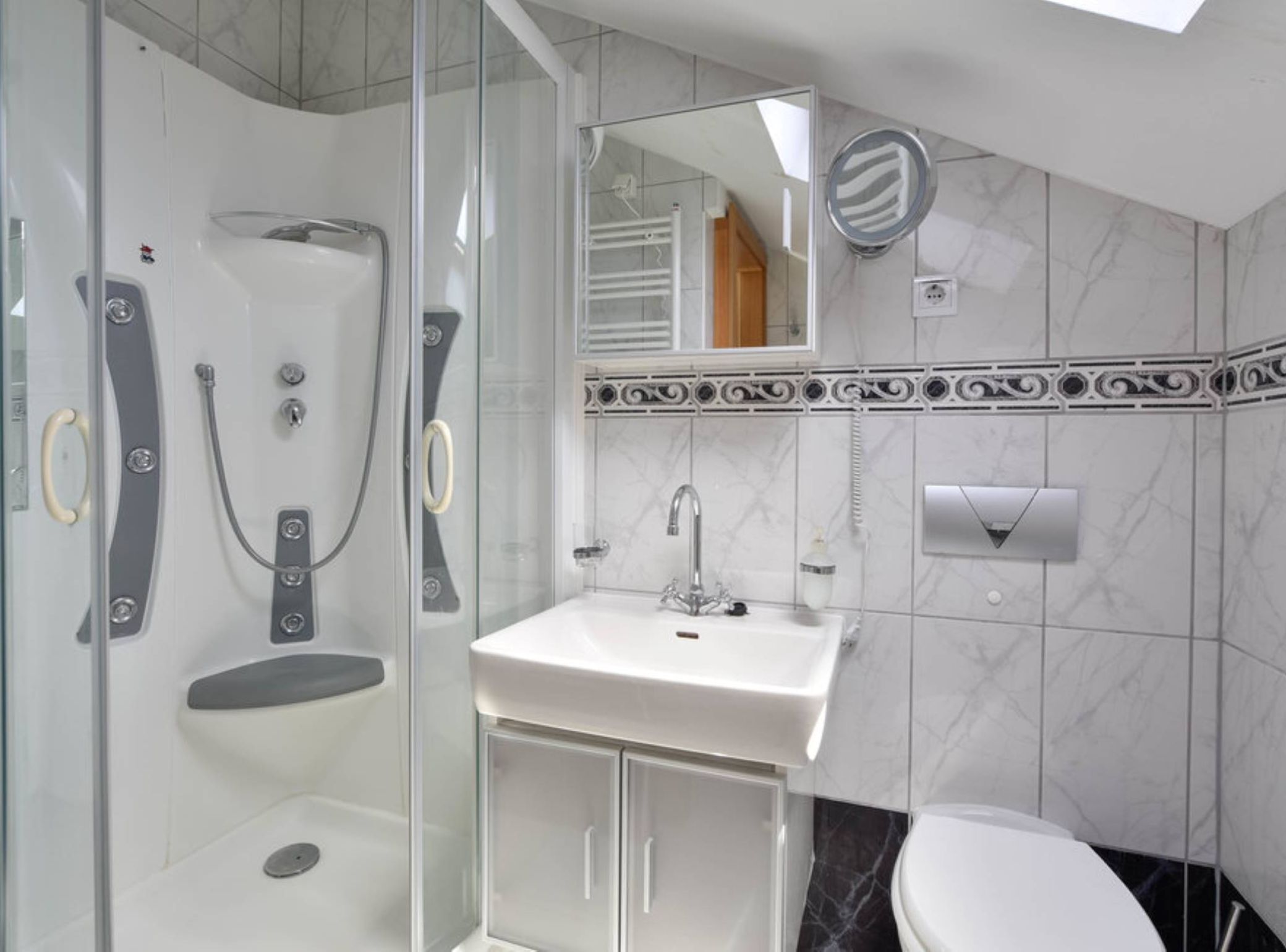 Un baño moderno con ducha de vidrio, lavamanos blanco y retrete.