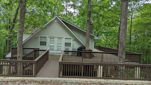 A two-story cabin with a deck, surrounded by trees. -  1-bdrm house with fireplace, AC and WiFi with 20 acres of  trees scenic deck. (Kingston)