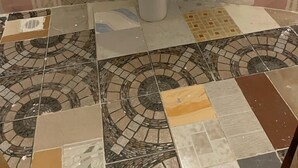 A bathroom with a white pedestal sink, tiled walls, and a mosaic tile floor.