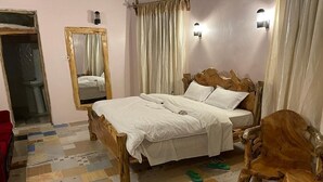 A bedroom with a wooden bed, a mirror, a nightstand, and a chair.