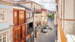 A narrow street with multi-story buildings, balconies, and a few pedestrians. - Rooms4you 2 in historic center of Braga (Braga)