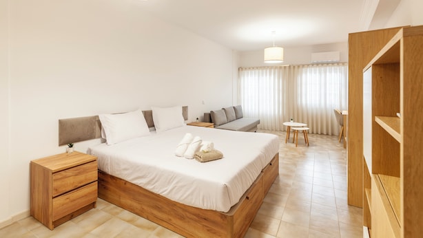 A modern hotel room with a large bed, a wooden nightstand, a small table, and a seating area with a sofa and chairs. - Rooms4you 2 in historic center of Braga (Braga)