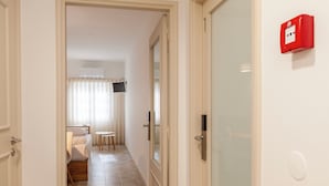 A hotel hallway with a bed, a small table, and a red emergency light on the wall. - Rooms4you 2 in historic center of Braga (Braga)