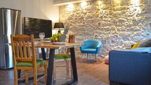 A modern kitchen with a stone wall, wooden dining table, chairs, and a blue armchair. - Elegant Rovinj Old Town Apartment (Rovinj)