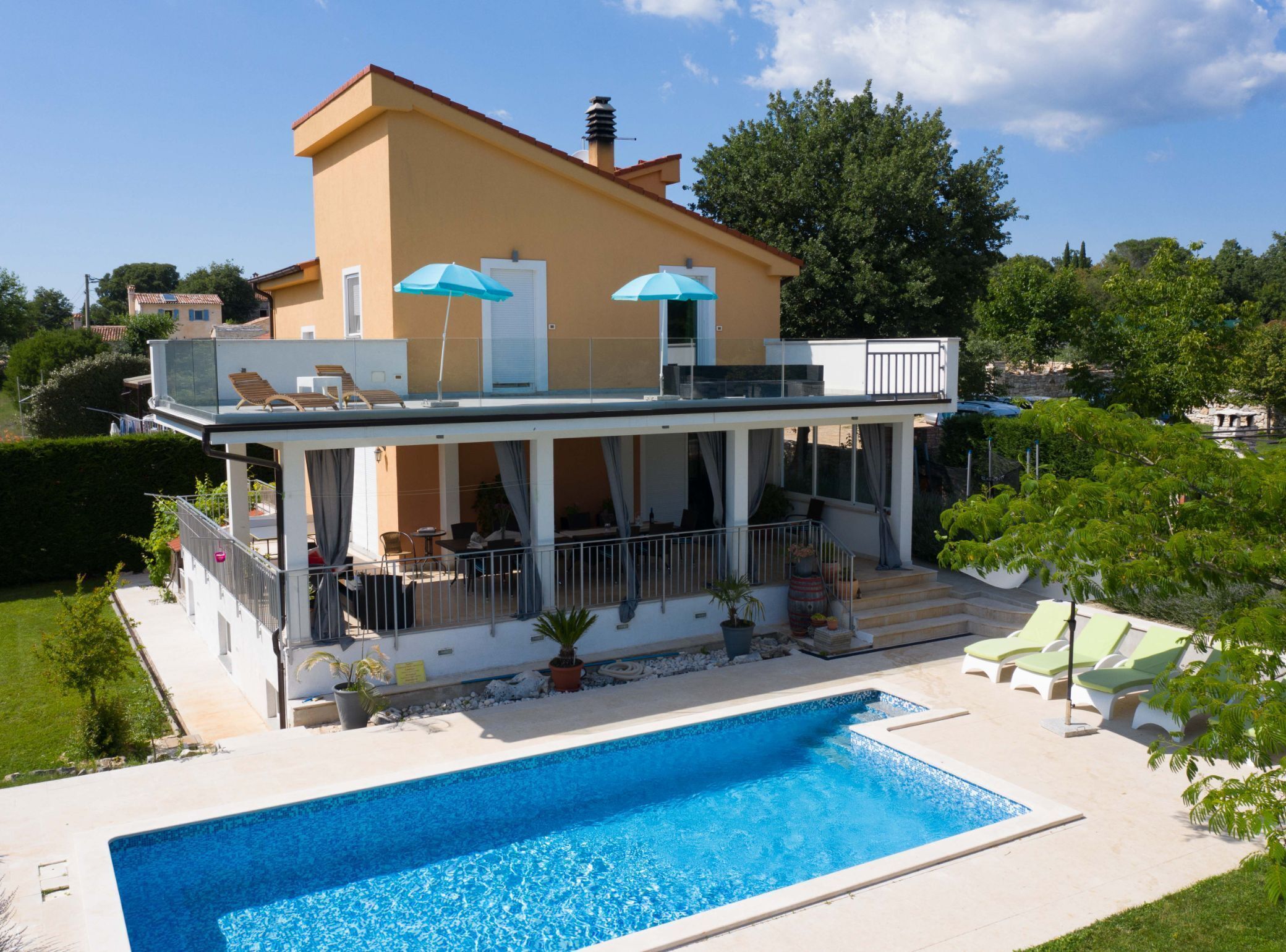 A modern two-story house with a swimming pool, outdoor seating, and a covered patio area.