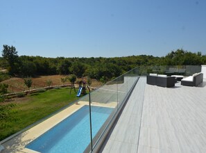 A rooftop pool area with a glass balustrade, outdoor seating, and a playground. - Exquisite Secluded Villa With Pool (Kanfanar)