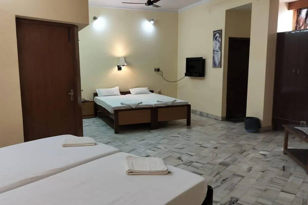 Habitació d'hotel amb llit, taula de nit, armari i televisió.