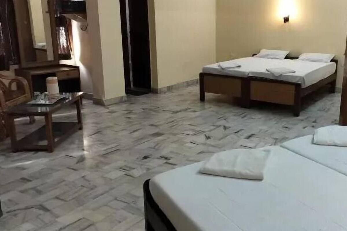 Habitació d'hotel amb llit, cadira, taula petita i llum penjada a la paret.