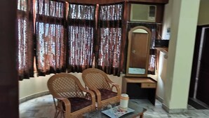 Quarto com duas cadeiras de vime, uma mesinha, um espelho e uma escrivaninha.