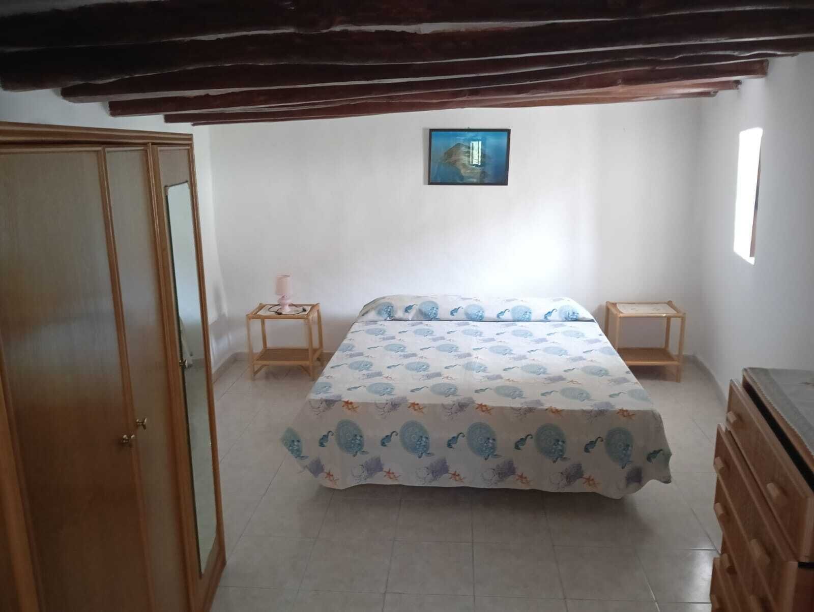 A bedroom with a bed, two bedside tables, a wardrobe, and a painting on the wall.