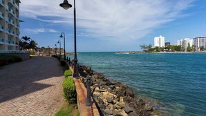A coastal walkway with a stone path, metal railings, and street lamps. - Wave Front Escape | Trendy Studio in Condado (San Juan)