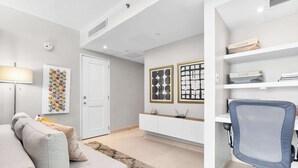 A modern living room with a sofa, a desk with a chair, and artwork on the walls. - Wave Front Escape | Trendy Studio in Condado (San Juan)