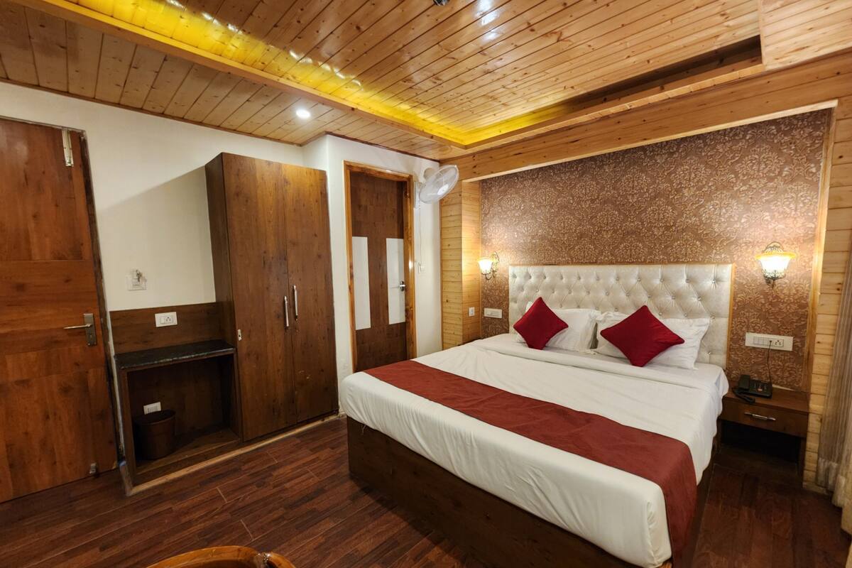 Une chambre d’hôtel avec un grand lit, une armoire en bois et un miroir.