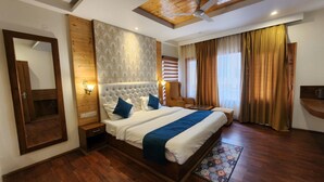 A spacious bedroom with a large bed, a wooden ceiling, a ceiling fan, and a view of the outdoors through a window with curtains. - Di Villa (Manali)