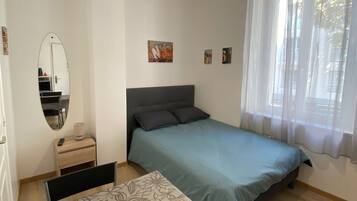 Ein Schlafzimmer mit einem Bett, einem Tisch, einem Spiegel und einer Pendelleuchte.