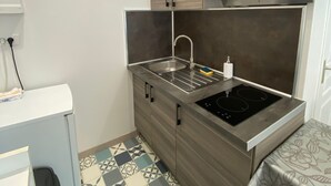 A compact kitchen with a built-in stove, a sink, and a microwave. - Le repos des Thermes (Rochefort)