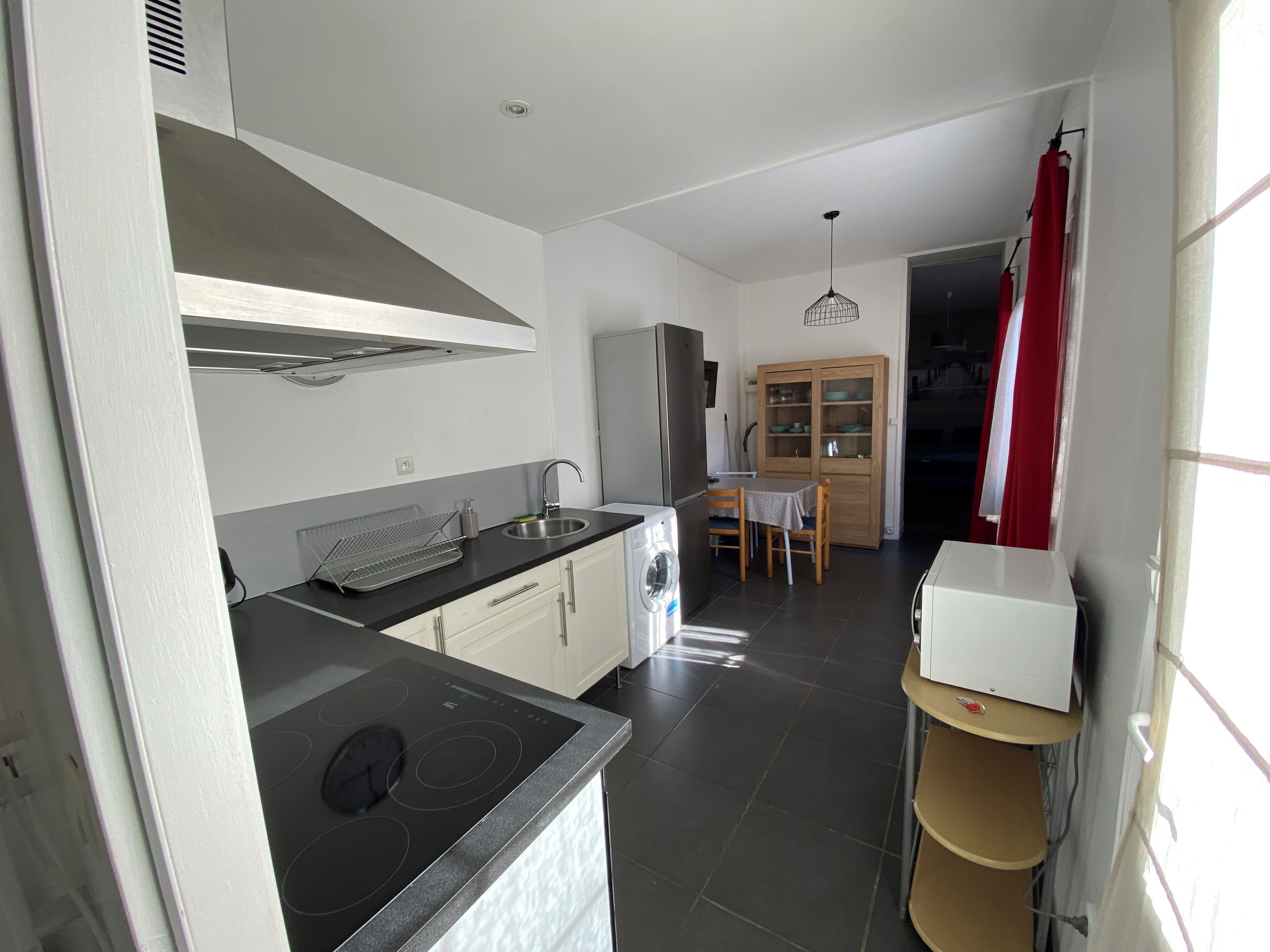 A compact kitchen with a stove, sink, and wooden cabinet.