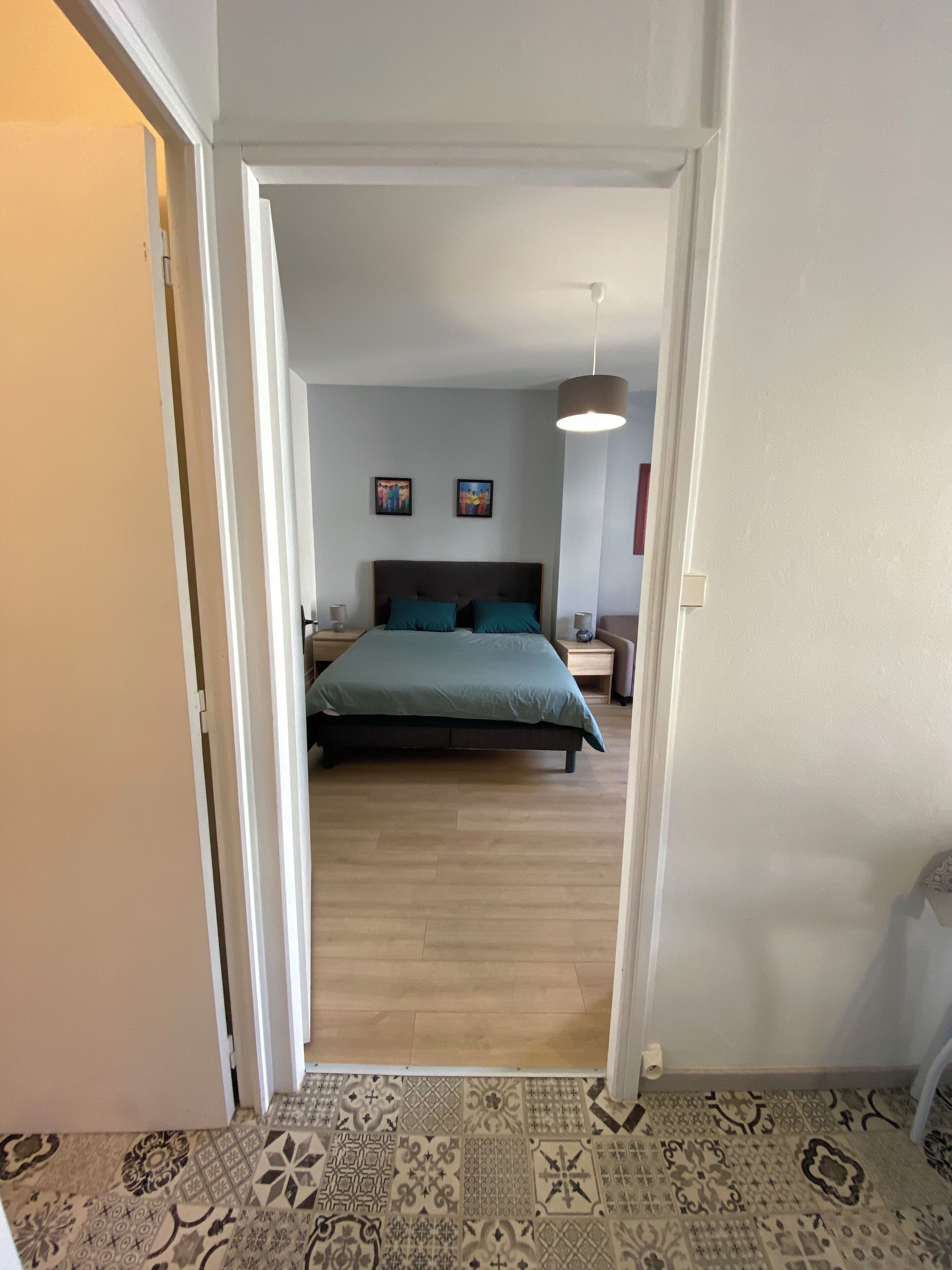 Een slaapkamer met een bed, nachtkastjes en een hanglamp.
