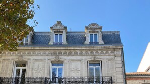 A historic building with a symmetrical facade, large central doors, and a balcony with ornate iron railings. - Le repos des Thermes (Rochefort)