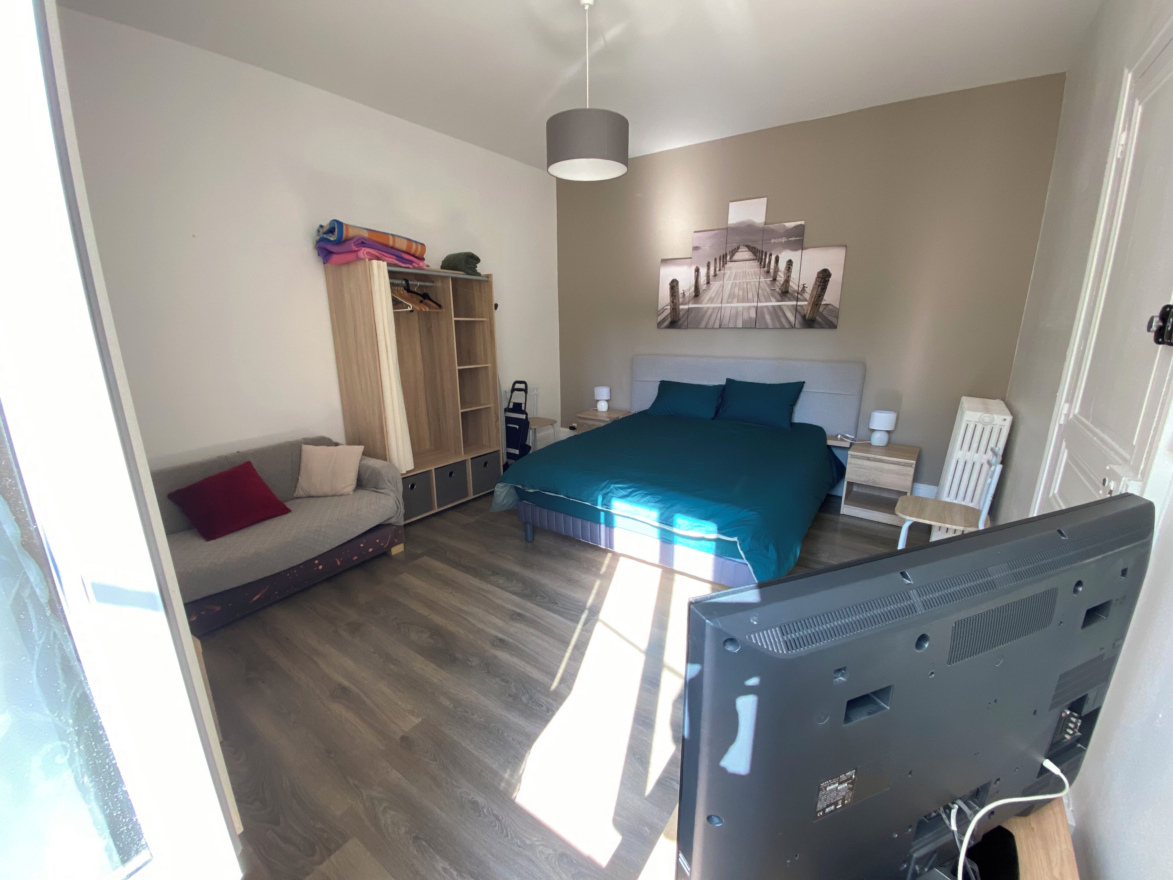 A bedroom with a bed, a wardrobe, a desk, and a chair.