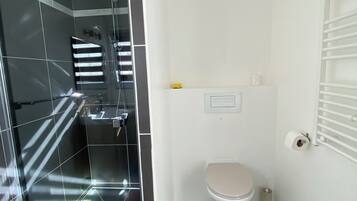 A compact bathroom with a shower, toilet, and a small sink.
