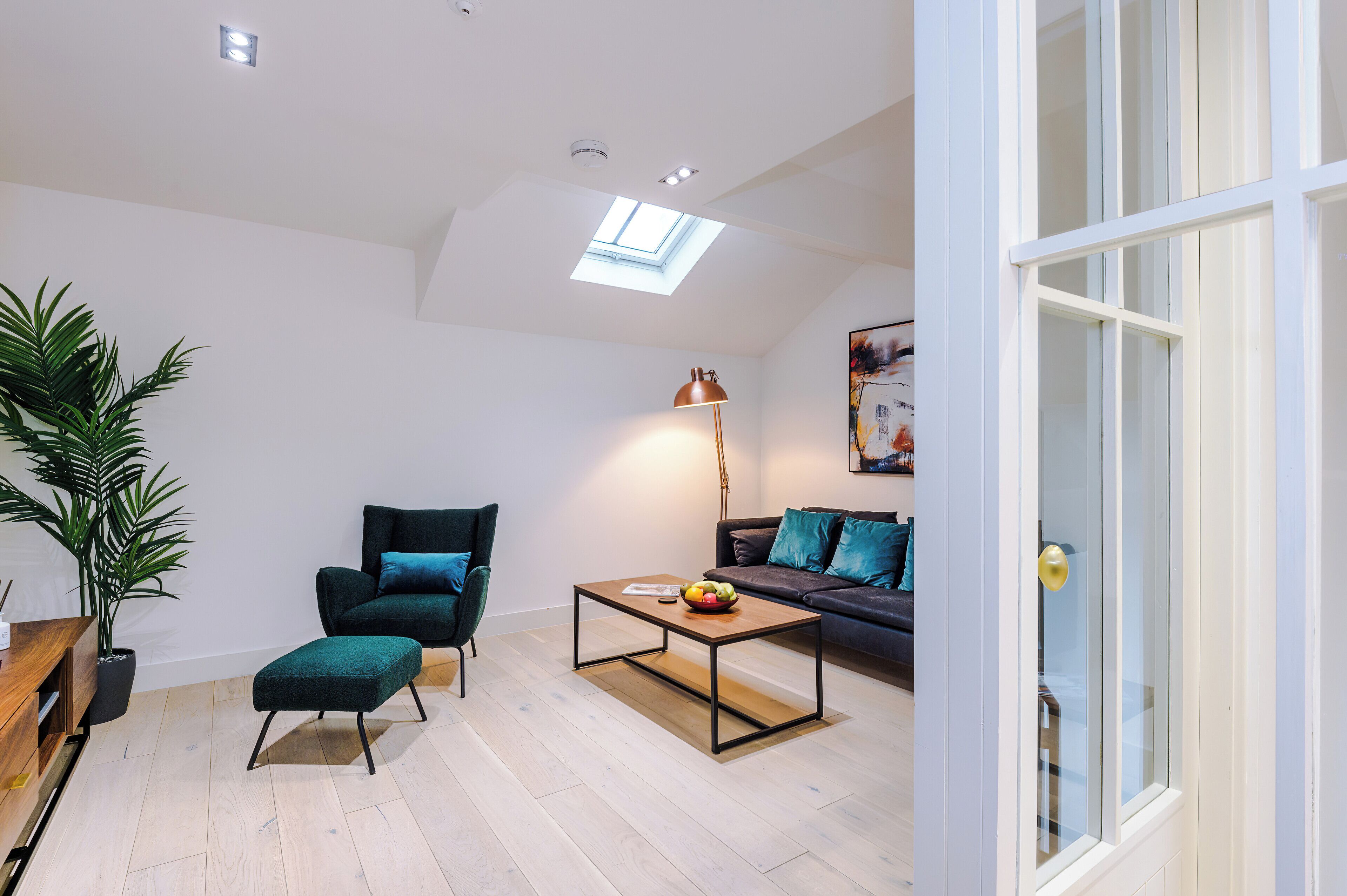 A modern living room with a sofa, a coffee table, and a potted plant.