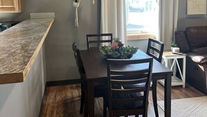 A dining area with a wooden table and chairs, a kitchen with a wooden countertop, and a window with curtains. - Modern 2-bed with full kitchen, in-unit laundry, and off-street parking. Near downtown Fairbanks. (Fairbanks)