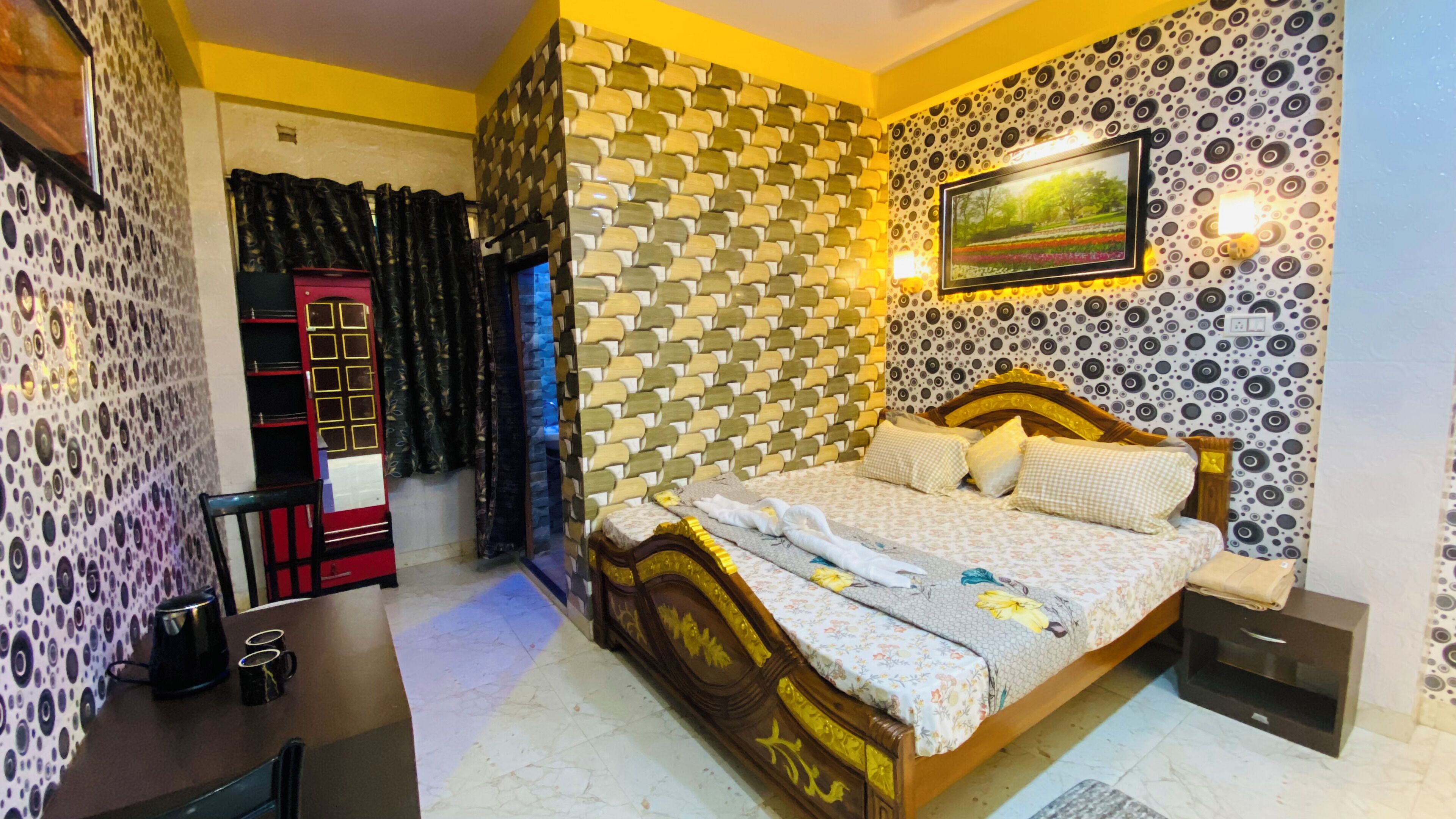 A bedroom with a patterned wall, a bed with floral bedding, a nightstand, a lamp, and a picture on the wall.