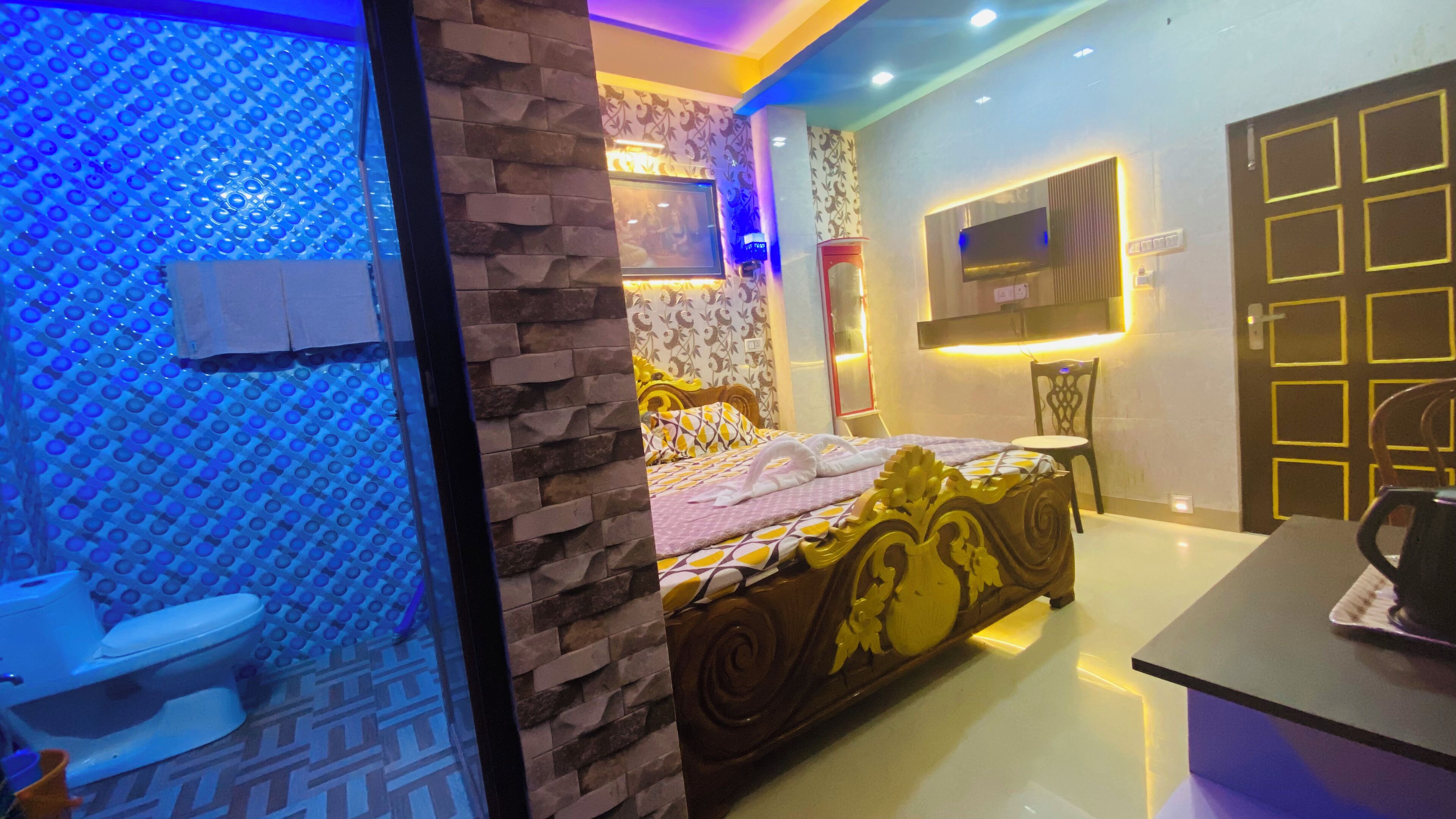 A hotel room with a bed, a TV mounted on the wall, a bathroom with a toilet, and a sink.