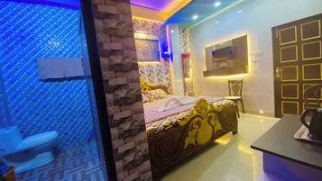 A hotel room with a bed, a TV mounted on the wall, a bathroom with a toilet, and a sink.