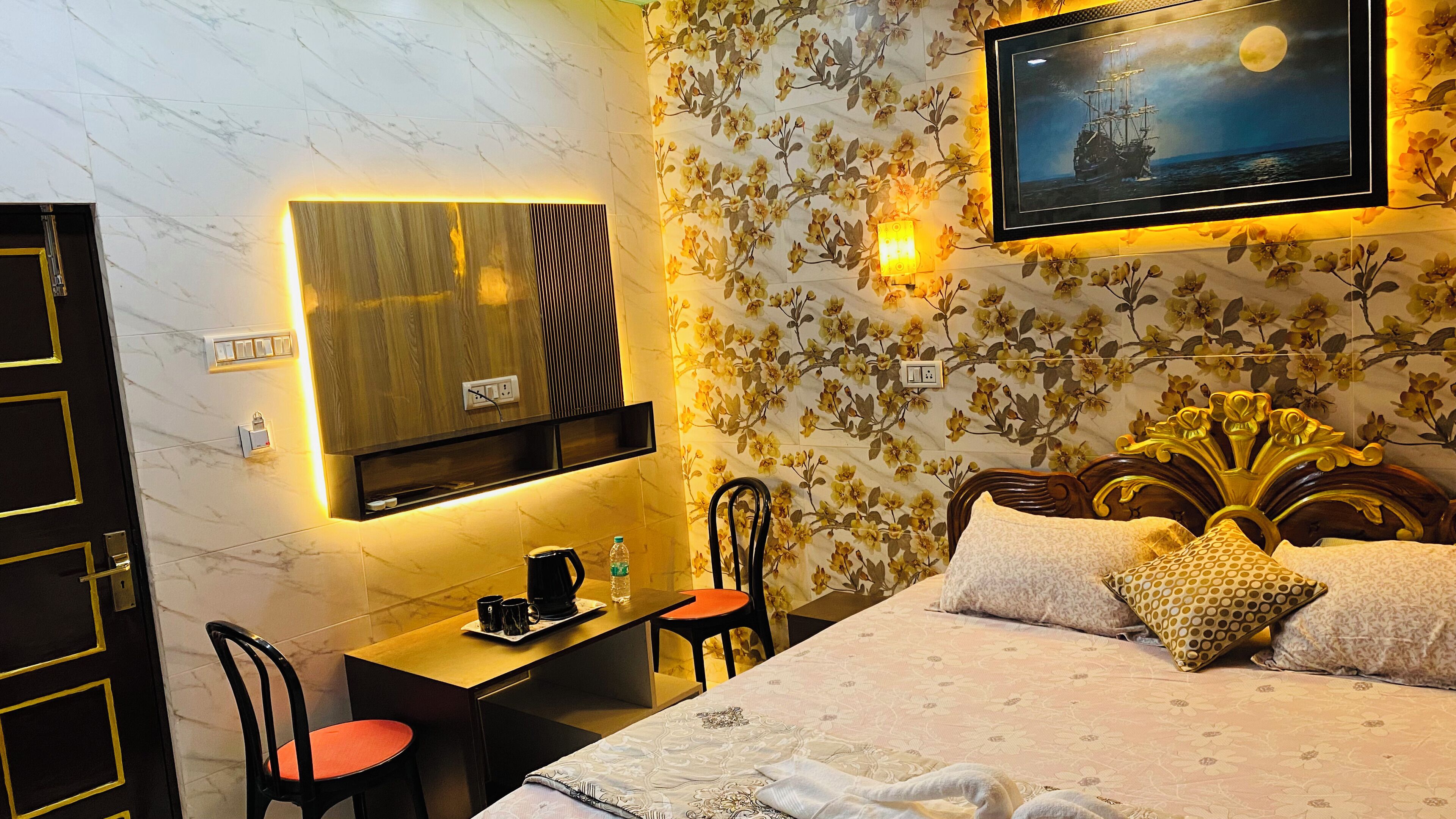 A hotel room with a bed, a desk, a chair, and a television mounted on the wall.