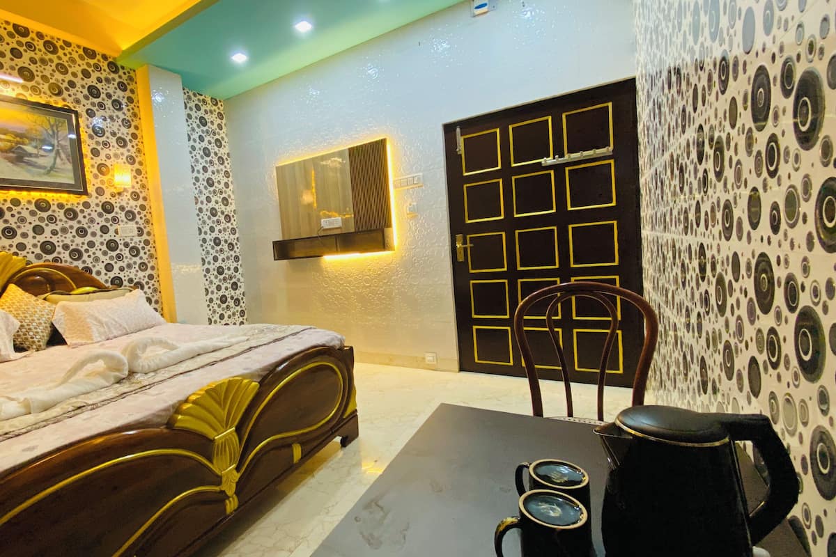 A hotel room with a bed, a table with two mugs, a chair, a door with a geometric pattern, and a wall with a circular pattern.