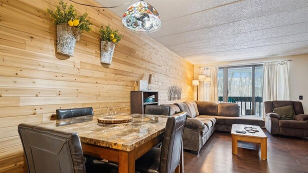 Ein gemütliches Wohnzimmer mit Holzwand, einem Essbereich mit einem Marmortisch und einer Couch.