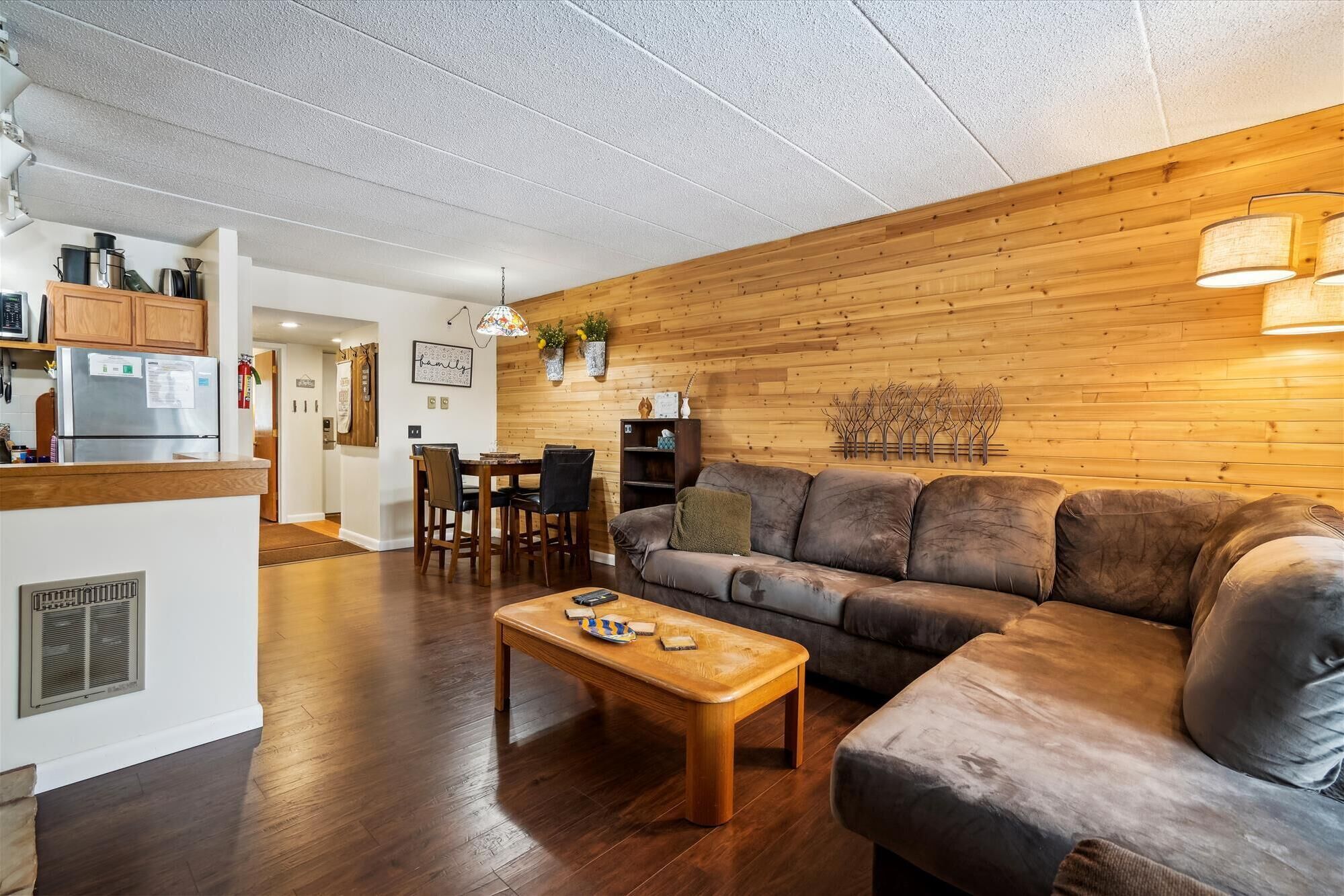 A cozy living room with a wooden wall, a leather sofa, and a wooden coffee table.