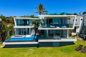 A modern two-story house with a swimming pool, a well-maintained lawn, and a clear blue sky. - Luxico Beaches at Sunrise (Heated Pool) (Sunrise Beach)
