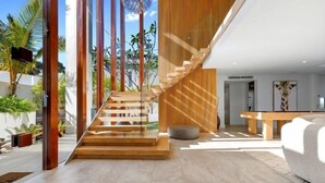 Ein modernes Interieur mit einer Holztreppe, einem Essbereich und Blick ins Freie.