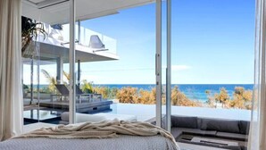 Ein Schlafzimmer mit einem großen Bett, Meerblick und einem Balkon mit Gartenmöbeln.