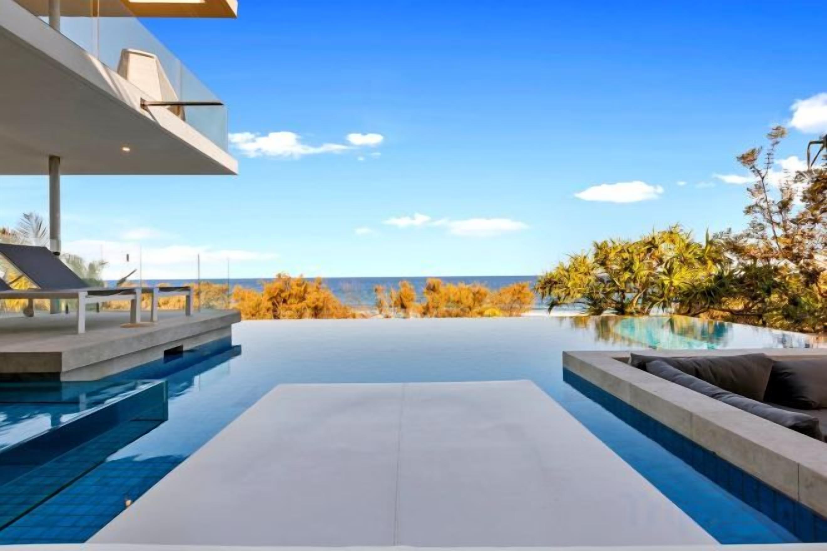 Un espace piscine extérieur moderne offrant une vue dégagée sur le ciel et les arbres.