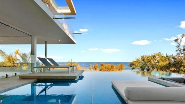 Ein moderner Infinity-Pool mit freiem Blick auf den Ozean, einem überdachten Sitzbereich und einem minimalistischen Architekturstil.