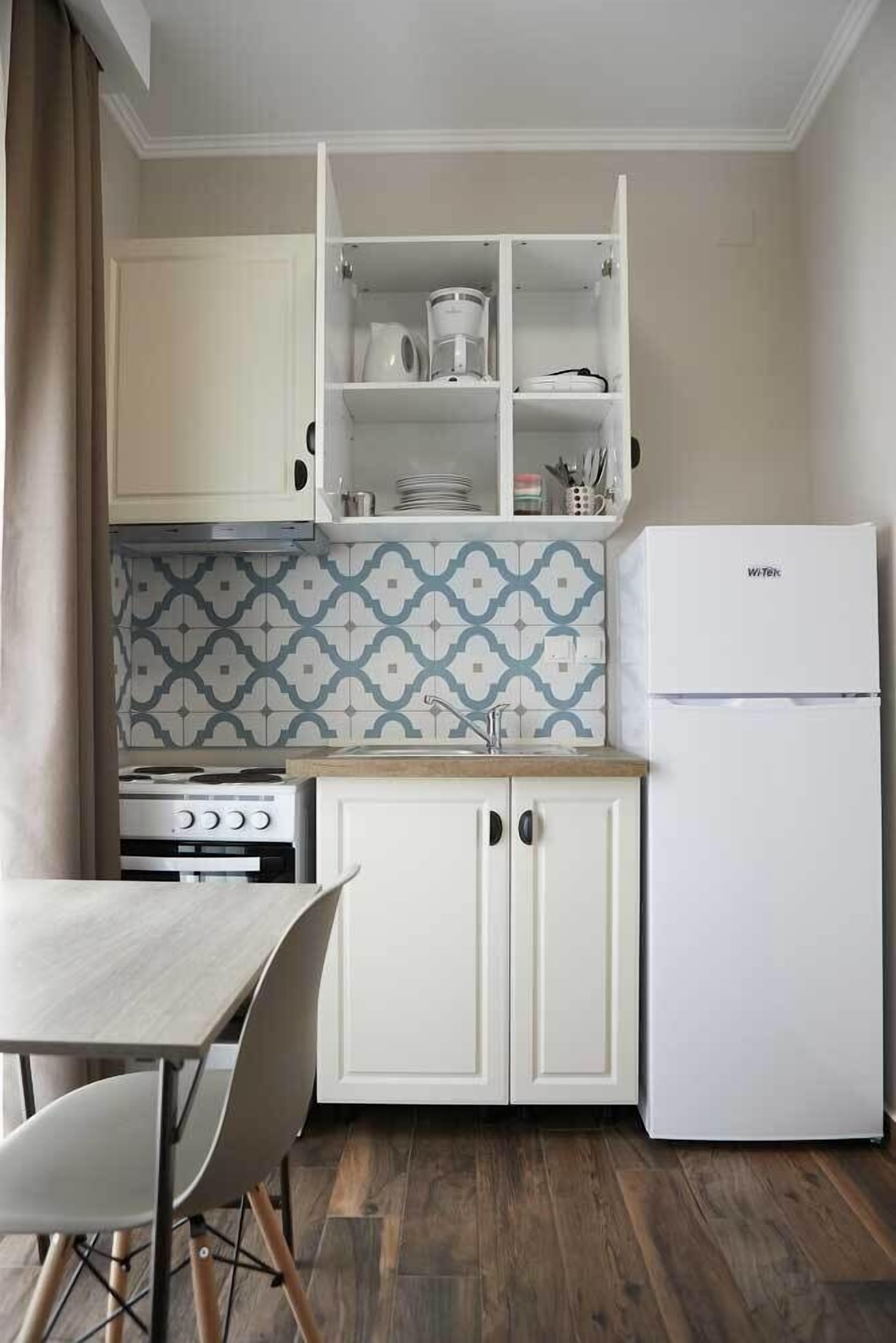 A compact kitchen with white cabinets, a stove, a sink, and a white refrigerator.