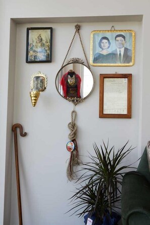 Un mur orné de divers objets, notamment un tableau encadré, un miroir, un document, un objet décoratif et une plante.