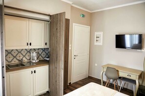 Une chambre d’hôtel compacte comprenant un coin cuisine, un lit, un bureau et un téléviseur.
