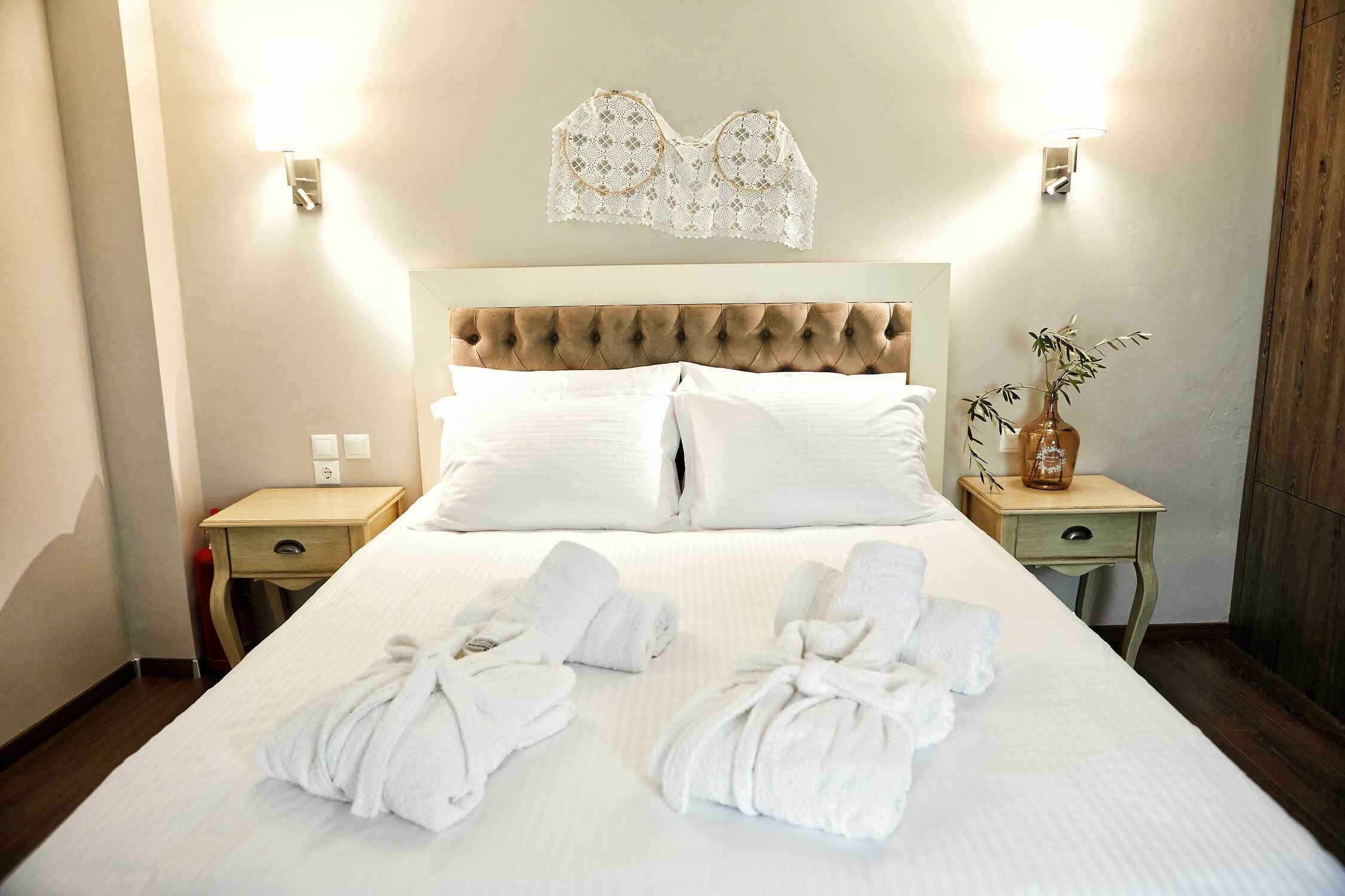 Una cama bien hecha con sábanas blancas, dos mesitas de noche y un adorno decorativo sobre la cama.