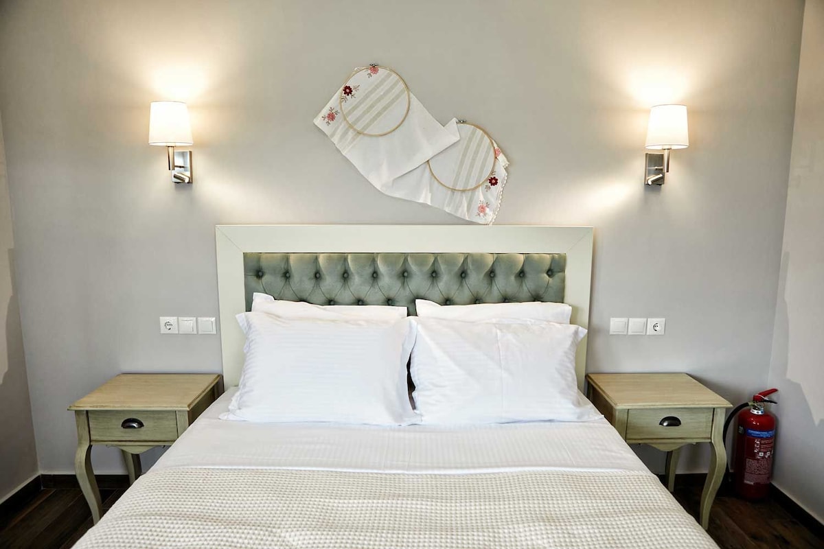 Ein Hotelzimmer mit einer gesteppten Kopfteil, zwei Nachttischen, einem Bett mit weißen Leinen und zwei Wandleuchten.